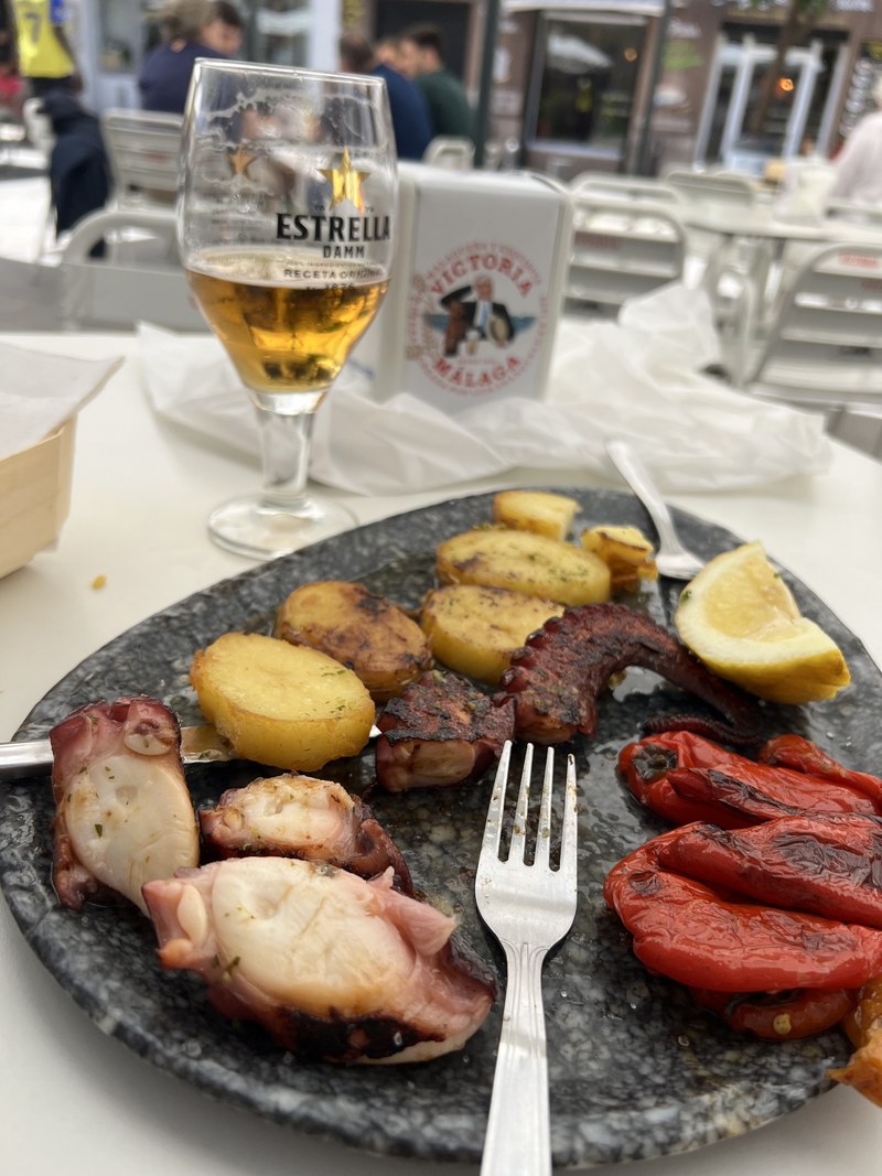 A drink and the tapa that arrived with it, unasked and included: octopus, potatoes and grilled red pepper.